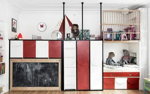 Kreative geschwisterzimmer ideen: Kinder spielen in einem bunten Zimmer mit Hochbetten, Rutsche und Tafel.