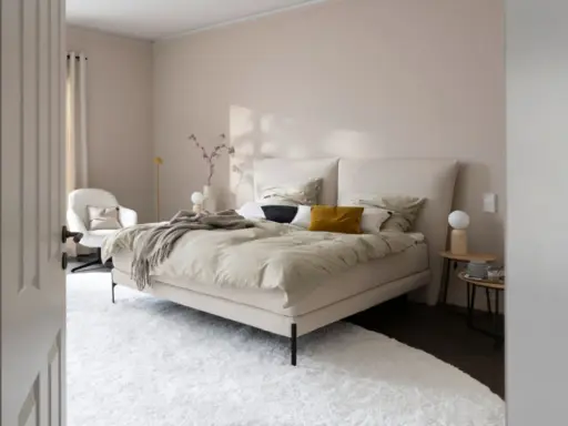 Beige schlafzimmer ideen: einladendes Bett mit beiger Bettwäsche, Akzentkissen und Decke. Weißer Sessel, Nachttische und Teppich schaffen Gemütlichkeit.