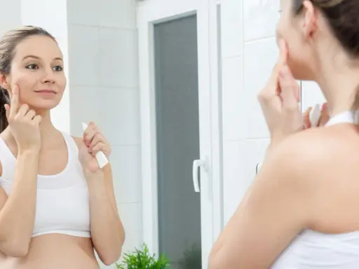 Schwanger und kämpft mit unreiner Haut? Eine junge Frau trägt eine Creme auf ihr Gesicht auf, um Hautunreinheiten während der Schwangerschaft zu behandeln.
