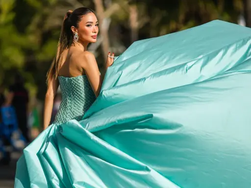 Elegante Dame im mintgrünen Ballkleid, das den Black Tie Dresscode für Damen perfekt verkörpert. Ihr Kleid weht im Wind.