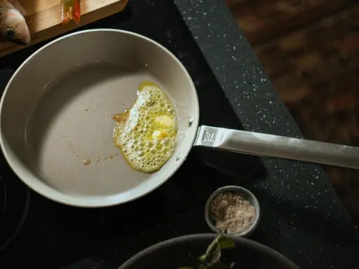 Eine beschichtete Pfanne reinigen: Butter schmilzt und blubbert, bereit für den Fisch.