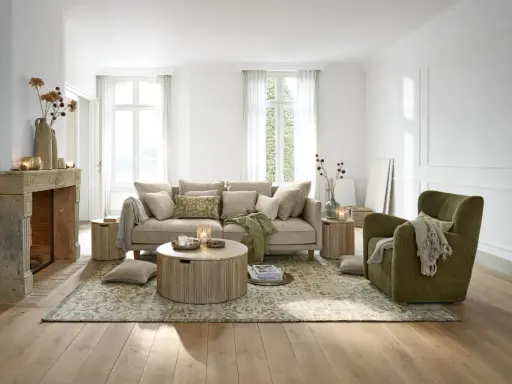 Gemütliches **interior wohnzimmer** mit beigem Sofa, grünem Sessel, Kamin und Holzboden.