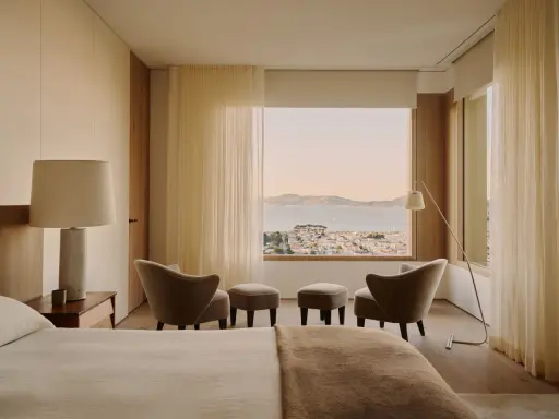 Ein Schlafzimmer mit Blick auf die Stadt und das Meer, gestaltet im Stil einer Feng Shui Wohnung. Sanfte Farben und natürliche Materialien schaffen Harmonie.