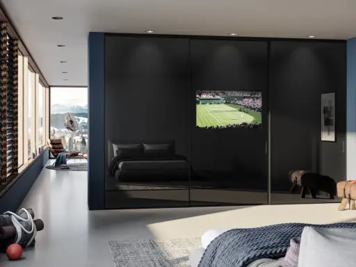 Ein moderner Kleiderschrank mit Spiegeltüren beherbergt einen integrierten Fernseher im Schlafzimmer, der ein Tennismatch zeigt.