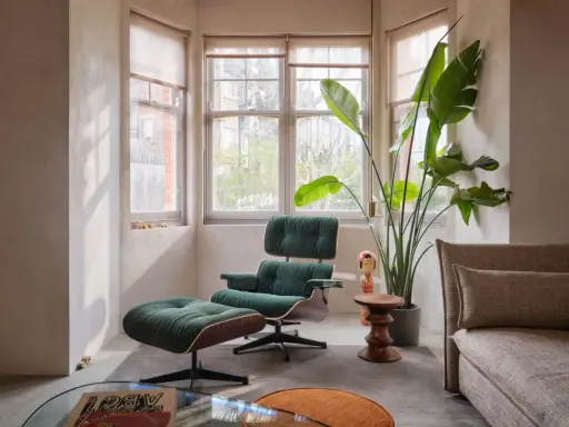 Gemütliche Ecke im midcentury stil mit einem grünen Cord-Sessel und Hocker, daneben eine große Zimmerpflanze und ein Beistelltisch.