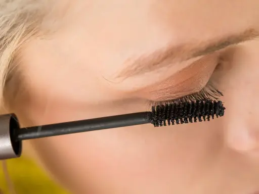 Ein Auge wird mit Mascara für ein leichtes Sommer Make-up betont. Die Bürste trennt und verlängert die Wimpern.