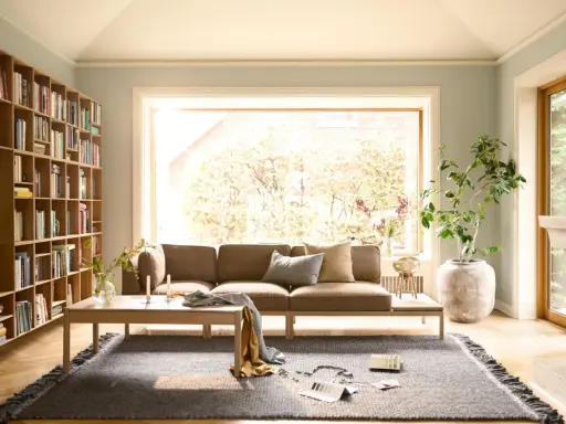 Gemütliche Anordnung Sofa Wohnzimmer mit Bücherregal, Kamin und großem Fenster.