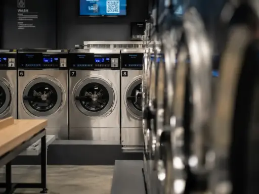 Reihe von Waschmaschinen in einem Waschsalon. Hoffentlich stinkt keine Waschmaschine nach Kanal.