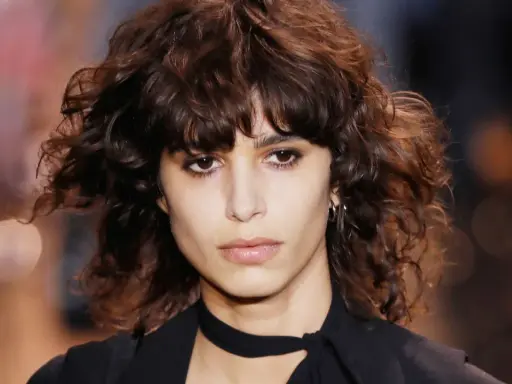 Ein Model mit einem lässigen shag cut und dunklen, welligen Haaren.