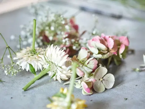 Zutaten für einen Blumenkranz: weiße Blüten, rosa Hortensien und zarte Schleierkräuter liegen bereit.
