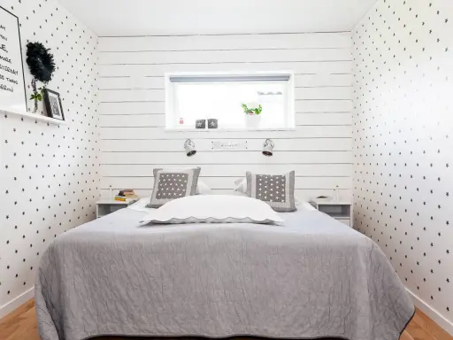 Gemütliches Schlafzimmer 10 qm einrichten: Sternen-Tapete, graue Decke, Nachttische und ein Bett mit Kissen.