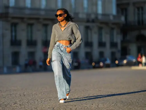 Stylische Frau in weit geschnittenen Jeans und kurzem Strickpullover, die zeigt, wie man wide leg jeans kombinieren kann.