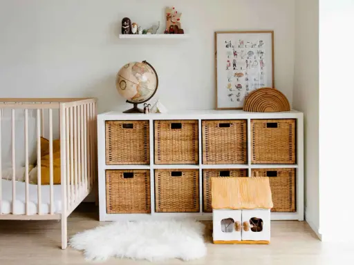 Ordentliches Kinderzimmer mit Gitterbett, Spielzeugkiste, Globus und Wandbild. Alles griffbereit für den Nachwuchs.