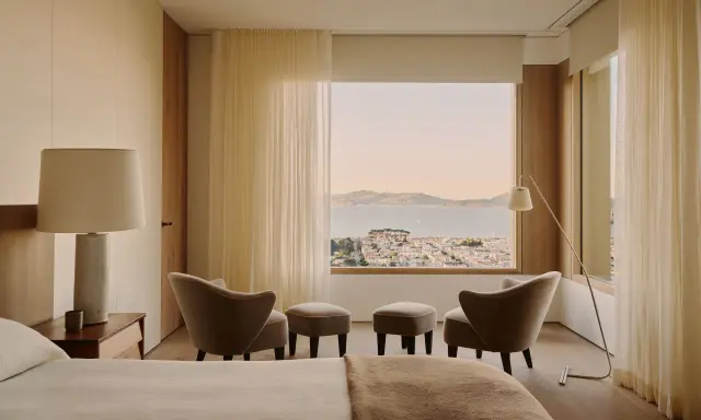 Ein Schlafzimmer mit Blick auf die Stadt und das Meer, gestaltet im Stil einer Feng Shui Wohnung. Sanfte Farben und natürliche Materialien schaffen Harmonie.