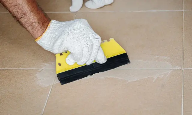 Mit einem gelben Spachtel werden die **Fliesen Fugen reinigen** und mit neuem Material gefüllt.