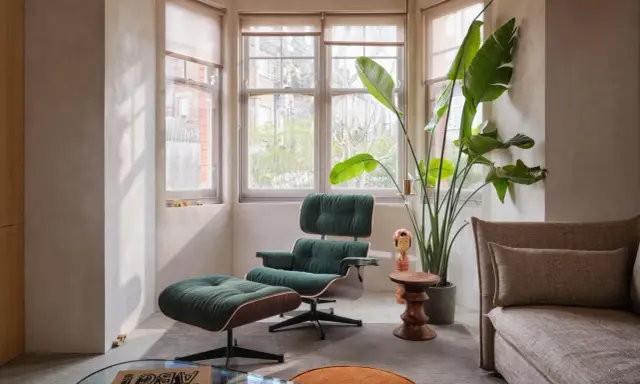 Gemütliche Ecke im midcentury stil mit einem grünen Cord-Sessel und Hocker, daneben eine große Zimmerpflanze und ein Beistelltisch.