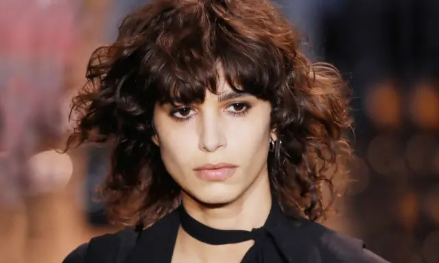 Ein Model mit einem lässigen shag cut und dunklen, welligen Haaren.
