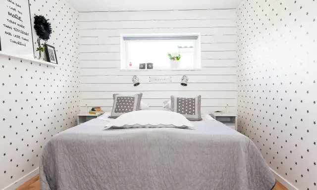 Gemütliches Schlafzimmer 10 qm einrichten: Sternen-Tapete, graue Decke, Nachttische und ein Bett mit Kissen.