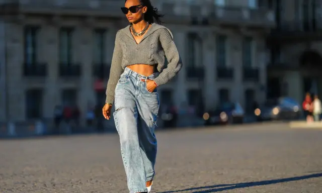 Stylische Frau in weit geschnittenen Jeans und kurzem Strickpullover, die zeigt, wie man wide leg jeans kombinieren kann.