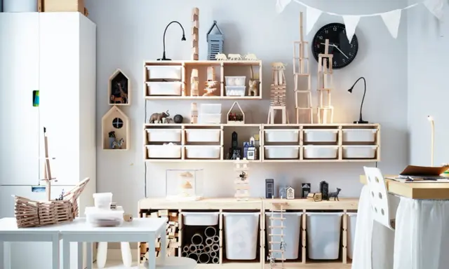 Ein schmal eingerichtetes Kinderzimmer mit viel Holz und weißen Aufbewahrungsboxen. Spielzeugtiere und Bauklötze sind ordentlich verstaut.