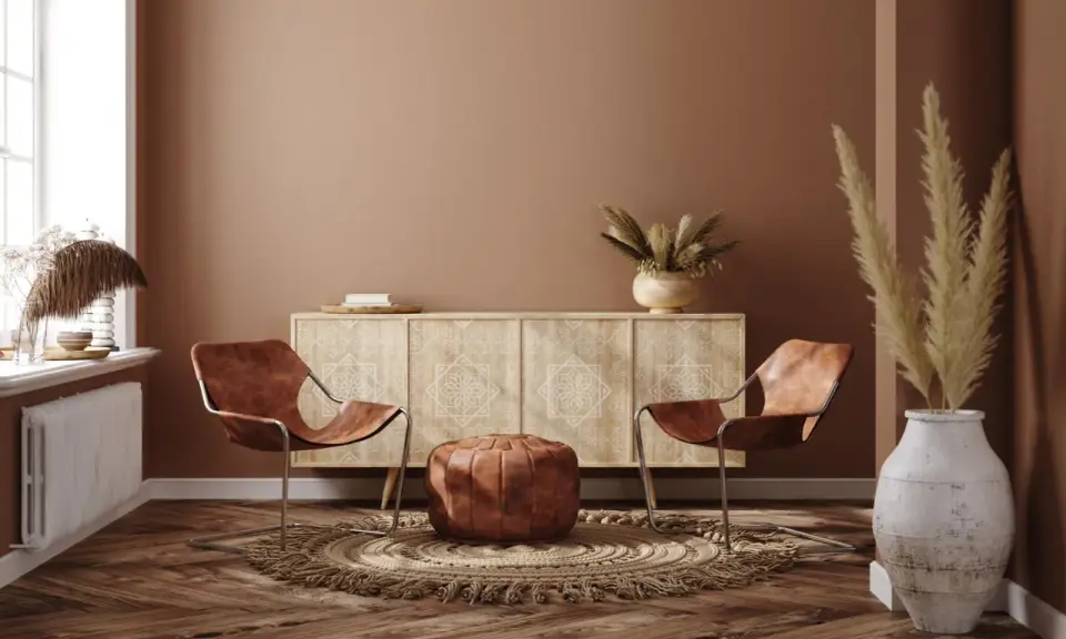 Ein gemütliches Wohnzimmer im Boho-Stil mit zwei Ledersesseln, einem runden Teppich, einem Sideboard und Trockenblumen.