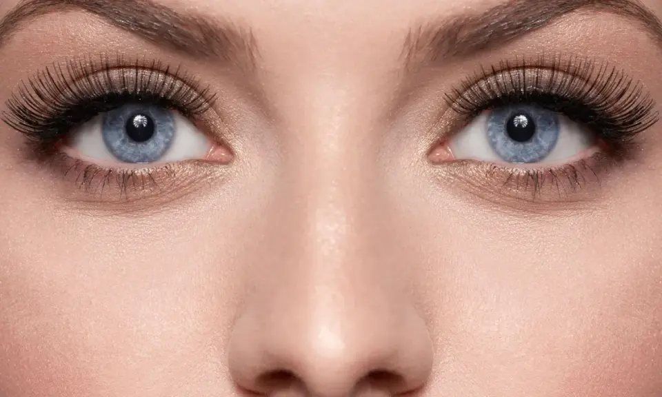 Blaue Augen mit dramatisch aufklebbaren Wimpern und goldenem Lidschatten.
