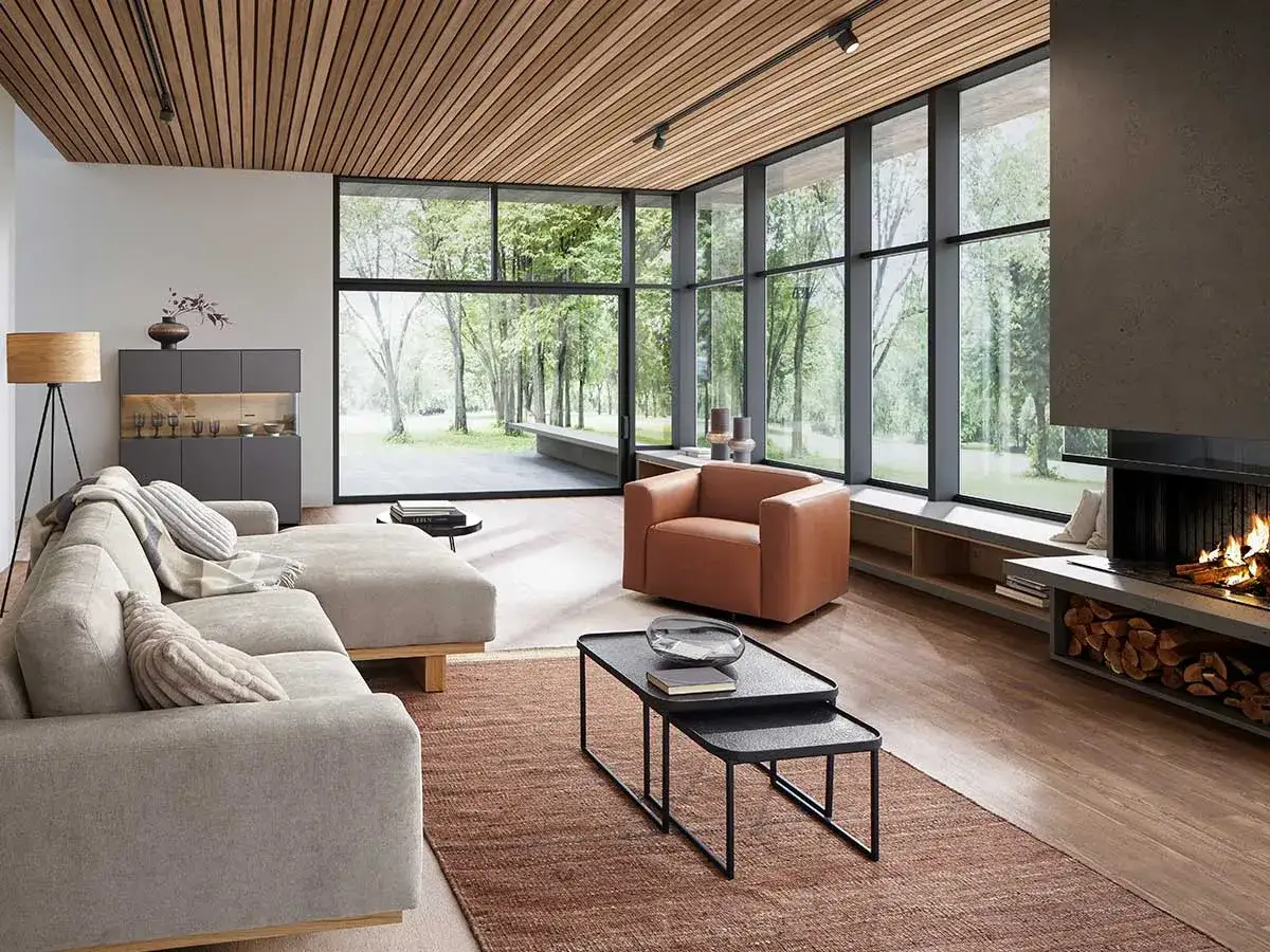 Modernes Wohnzimmer mit gro&szlig;em Fenster, Kamin und bequemer Couch. Perfekt, um Ihr Wohnzimmer umzugestalten und Gem&uuml;tlichkeit zu schaffen.