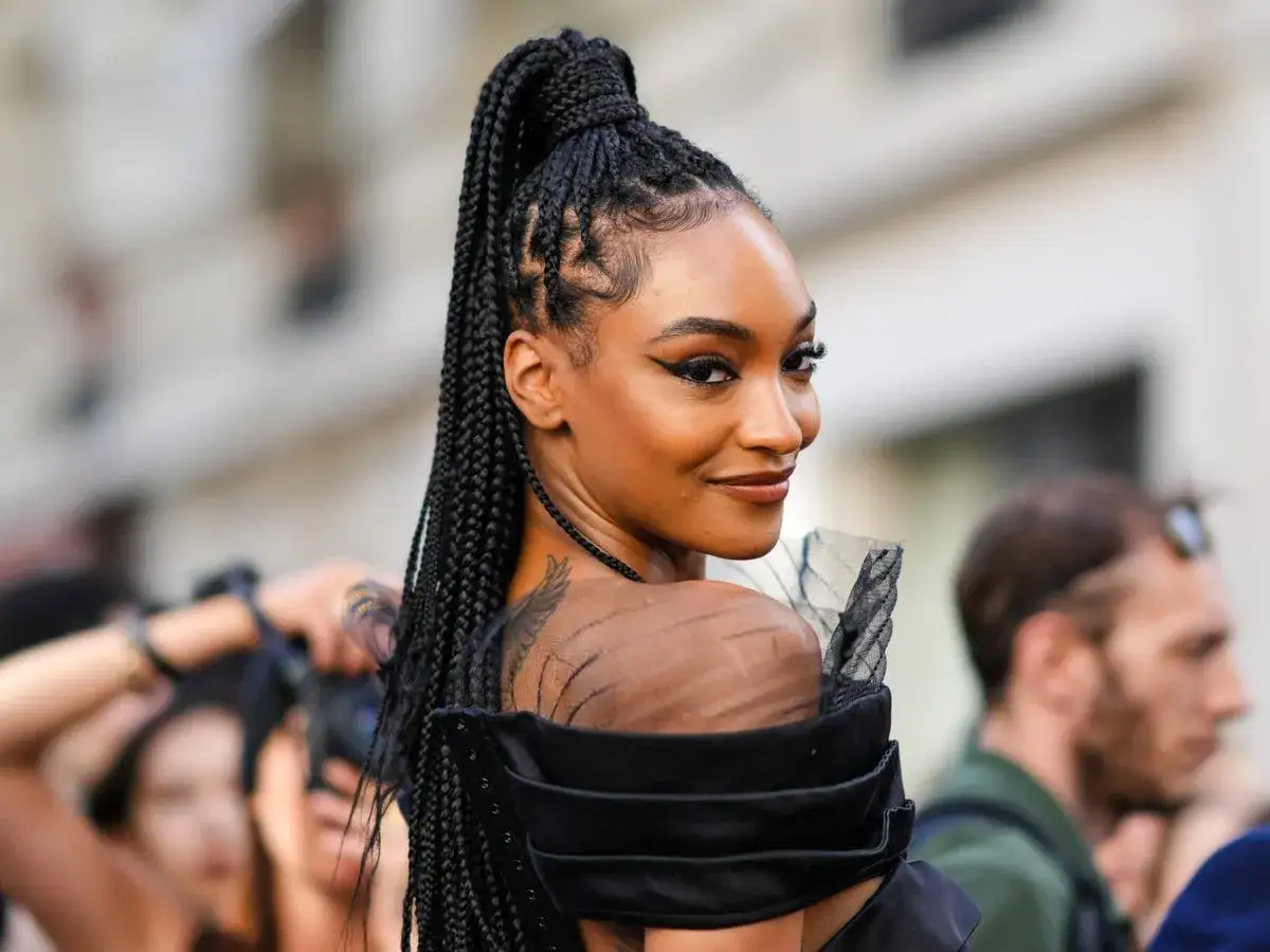 Ein Model mit langen, geflochtenen Haaren, die zu einem hohen Pferdeschwanz gebunden sind. Diese flechtfrisuren einfach und elegant.