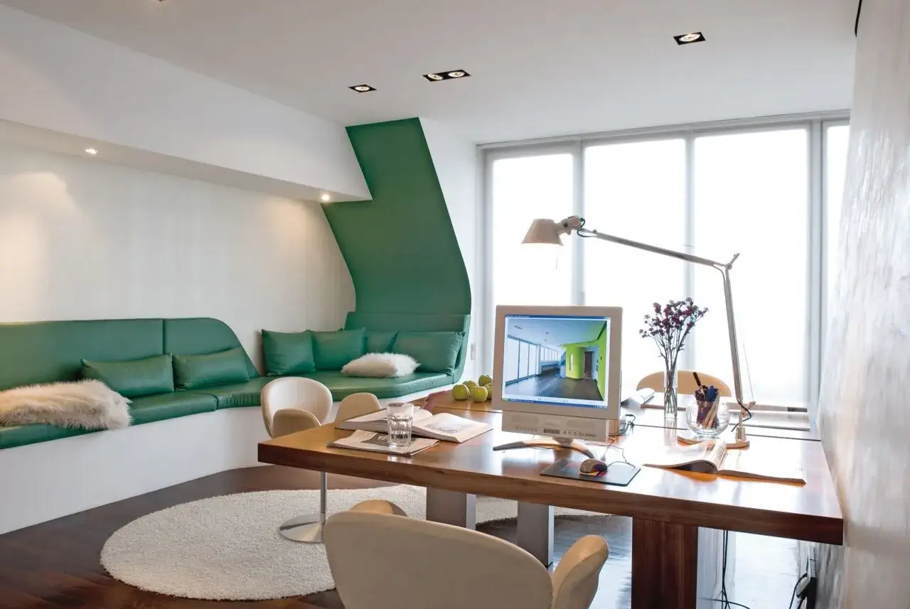 Moderne homeoffice ideen: ein gr&uuml;nes Sofa l&auml;dt zum Entspannen ein, w&auml;hrend der Schreibtisch mit Computer und Lampe zum Arbeiten bereitsteht.