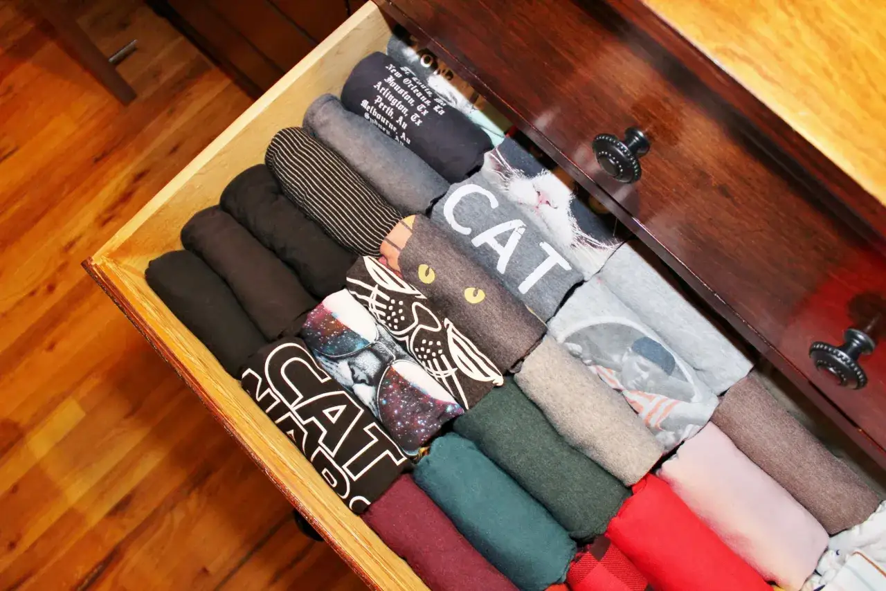 Ordnung im Kleiderschrank nach der Marie Kondo Methode: ordentlich gerollte T-Shirts mit lustigen Motiven wie Katzen und Weltraum.