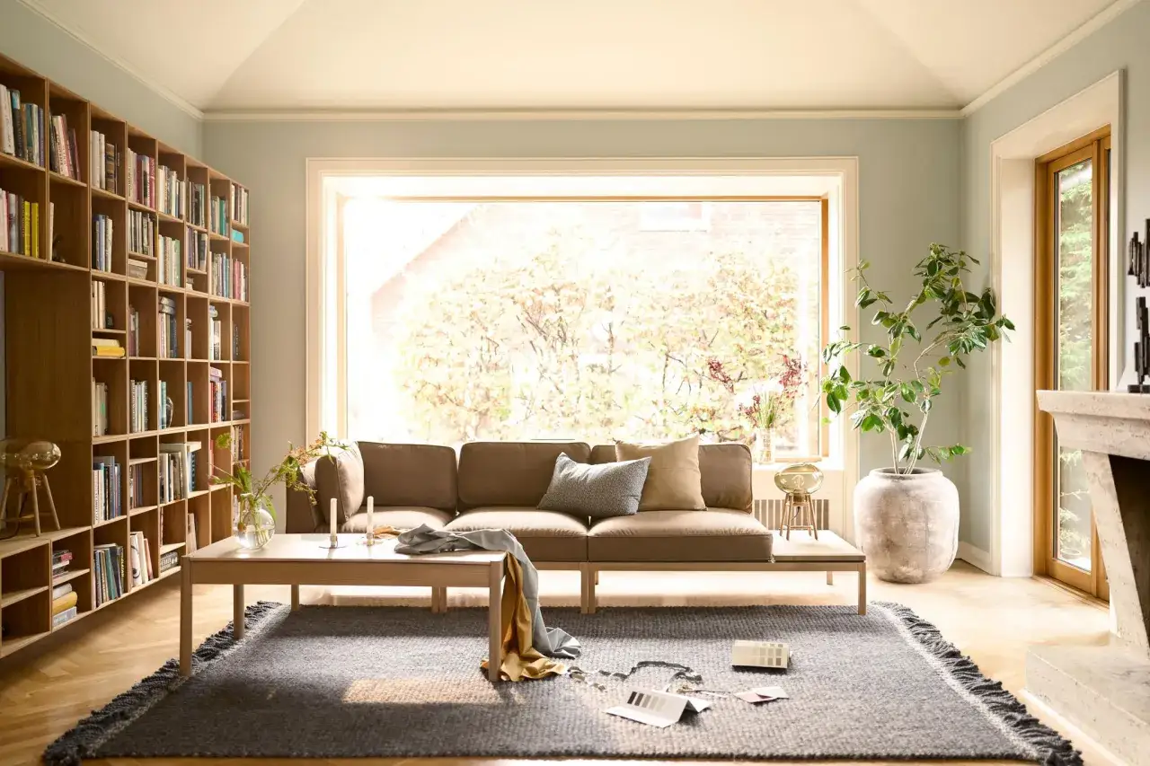 Gem&uuml;tliche Anordnung Sofa Wohnzimmer mit B&uuml;cherregal, Couchtisch und gro&szlig;em Fenster.
