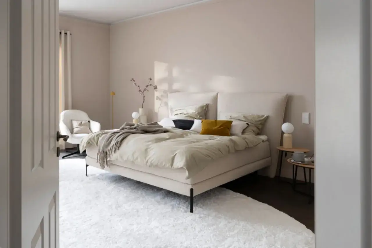 Beige schlafzimmer ideen: einladendes Bett mit vielen Kissen, gemütlicher Sessel, Teppich und dezente Deko.