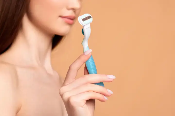 Eine Frau hält einen Rasierer, bereit für die Intimrasur.