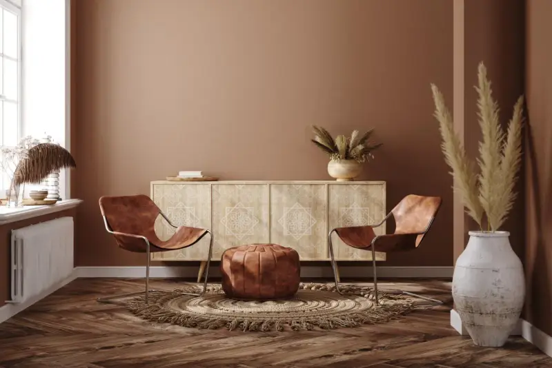 Ein gemütliches Wohnzimmer im Boho-Stil mit zwei Ledersesseln, einem runden Teppich, einem Sideboard und Trockenblumen.